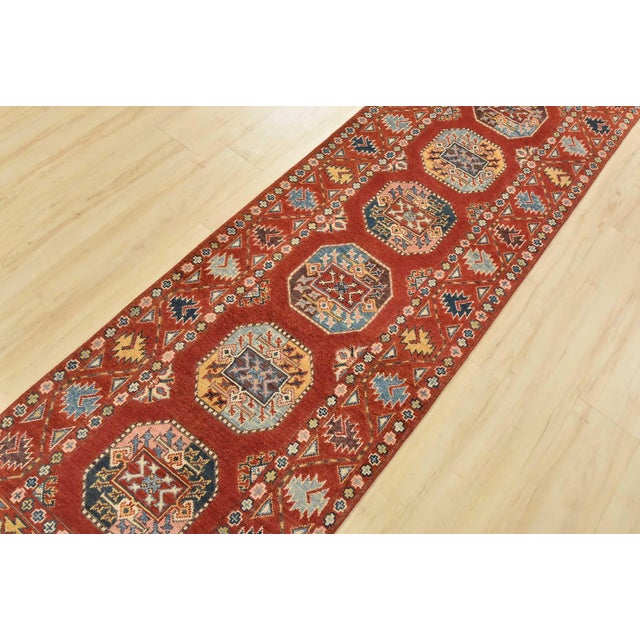 A tribal Caucasian Kazak runner hand-knotted with an all-wool pile on a cotton foundation. This oriental rug features a...