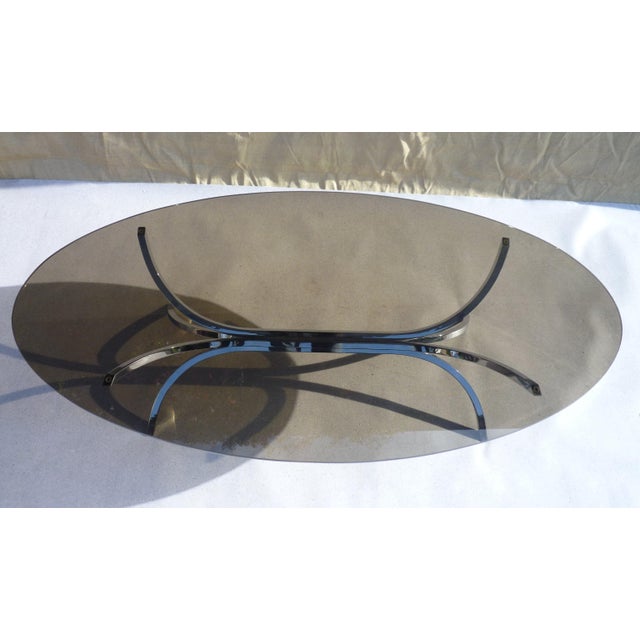 Oval coffee table with a 12mm bronze smoked glass top on a solid chromed steel base. The entire piece is in perfect...