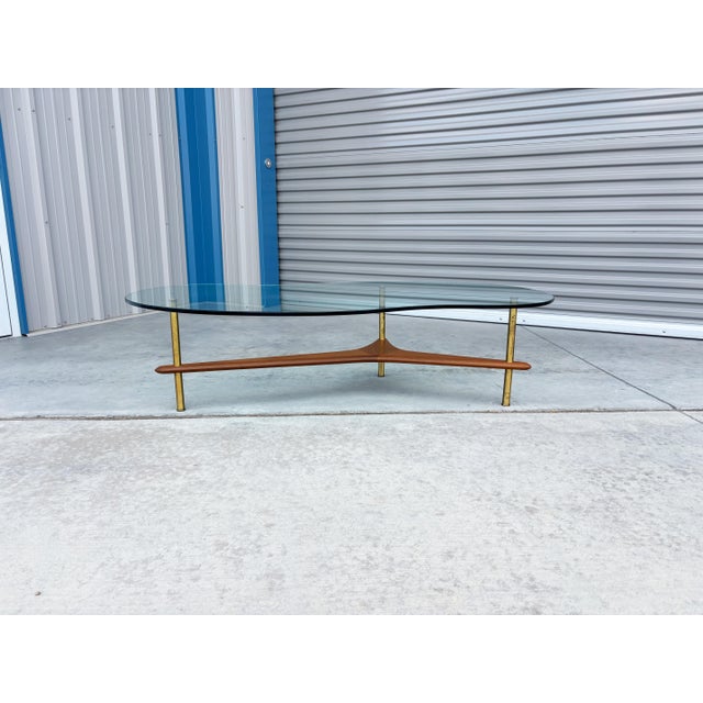 Mid-century walnut and brass freeform glass coffee table, designed and manufactured in the United States, circa 1960s....
