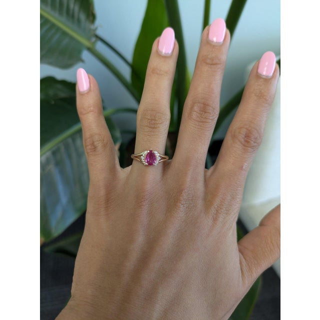 A natural pink sapphire glows in a soft, romantic pink at the centre of this solid 14K yellow gold ring, framed by...
