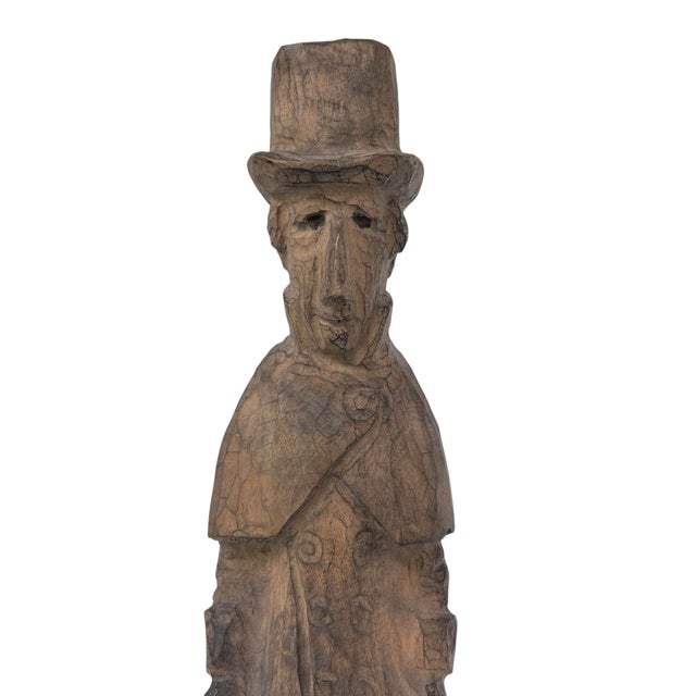 Hand-carved, Skandinavian-inspired folk art sculpture depicting a man in a top hat holding an umbrella and handled bag....