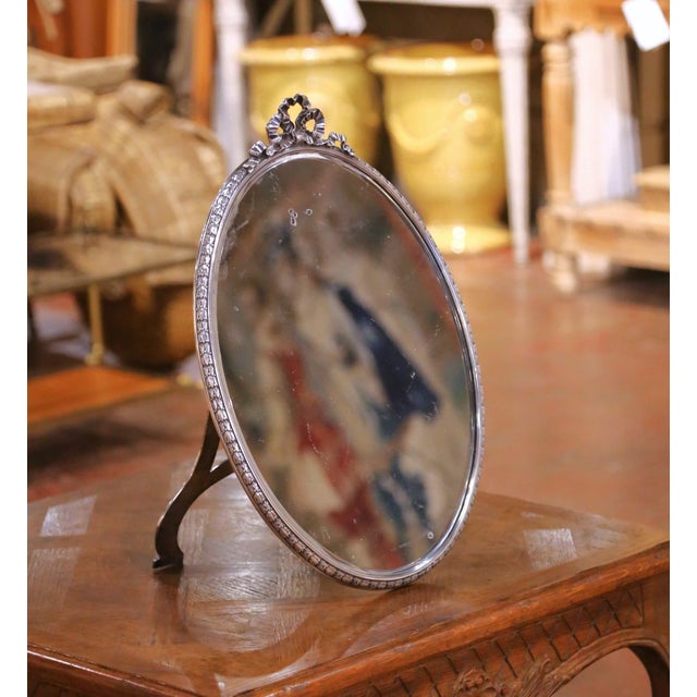 This elegant antique French vanity mirror was crafted circa 1900 and embodies the refined decorative spirit of the Belle...