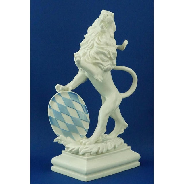 White porcelain sculpture depicting a rampant lion with a shield bearing the blue and white checkered pattern of the...