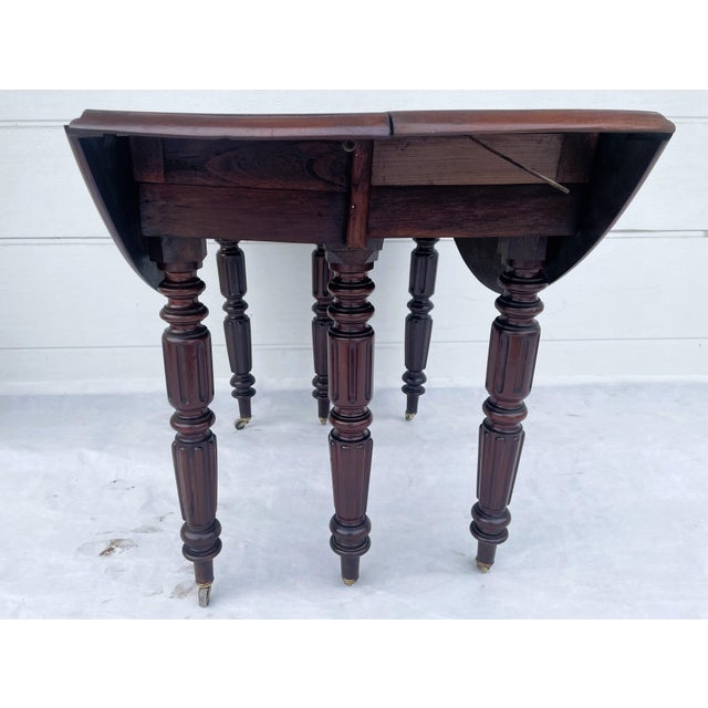 A remarkable antique english gateleg dining table crafted from solid hardwood, mahogany combining elegant fluted detailing...