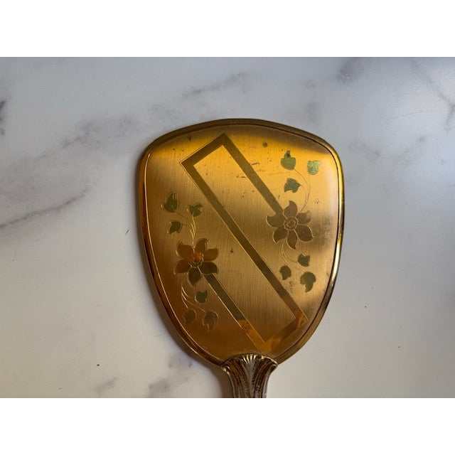 Pretty mid-century hand mirror as found on a ladies vanity. Floral pattern. Made of metal and glass. Mid-20thcentury.