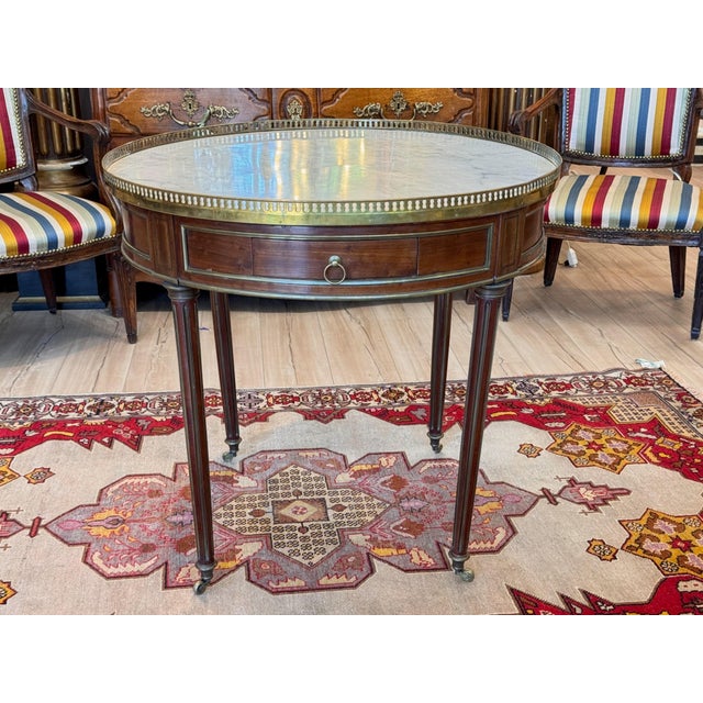 A late 19th C French Bouillotte table with white marble top set inside a pierced brass gallery. The frieze holds drawers...