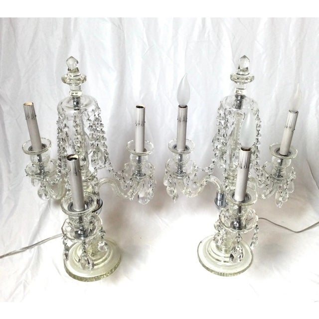 A pair of elegant cut glass and crystal three light girandole lamps. The center spire with three glass arms with light,...