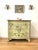 An early 20th-century sage green hand-painted serpentine chest of drawers decorated with floral motifs, scrollwork, and...