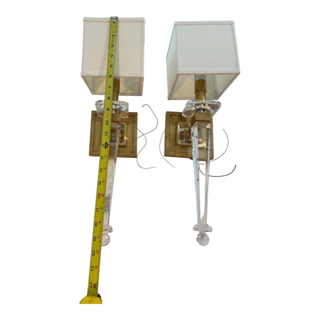 A pair of Hollywood Regency style crystal and brass wall sconces (often designed as torchieres or tapered obelisks). These...