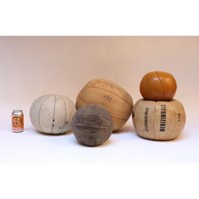 Collection of five European leather medicine ball, three (the orange, and two tan balls) are from Germany, all were...