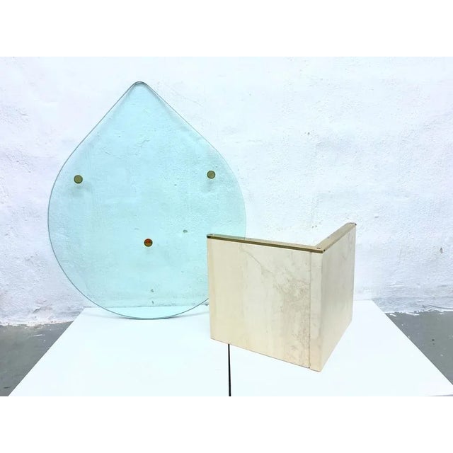 Side table from the 80s 90s. Travertine table base with brass finish, teardrop-shaped table top made of 2 cm thick glass....