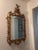 This elegant decorative mirror features an elaborate, ornate gilt frame characteristic of the Rococo or Baroque style. The...