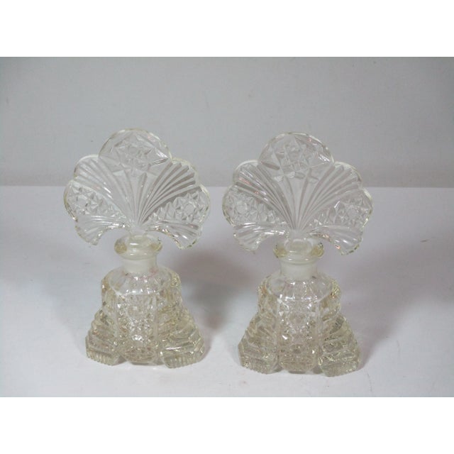 Vintage pair of Art Deco clear crystal perfume bottles. The ornate bottles have a layered step pattern on the sides with a...