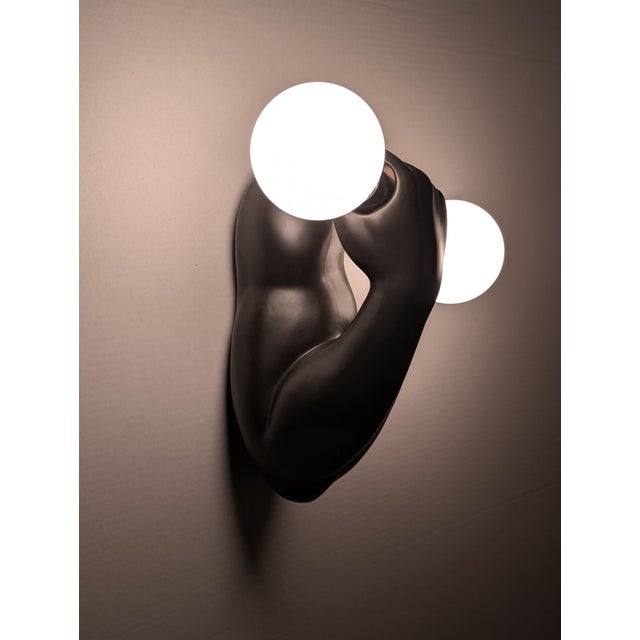 Wall sconce designed by J.C. Peiré, crafted from matte black ceramic, sculpturally designed as a muscular arm. The arm...
