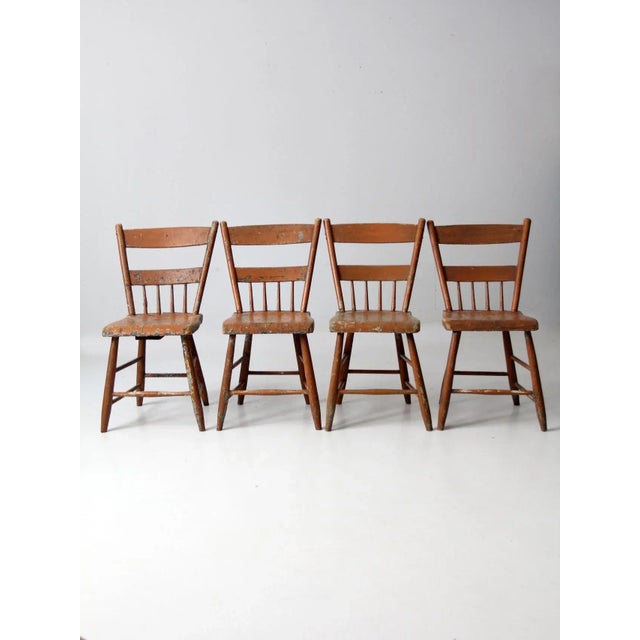 This is a collection of four antique primitive chairs. The rustic farmhouse chairs feature plank seats with spindle half-...