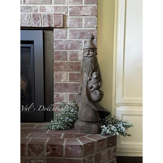 Val's Dollhouse is proud to present a tall hand carved wooden Santa holding a basket and toys. His jacket is carved in a...