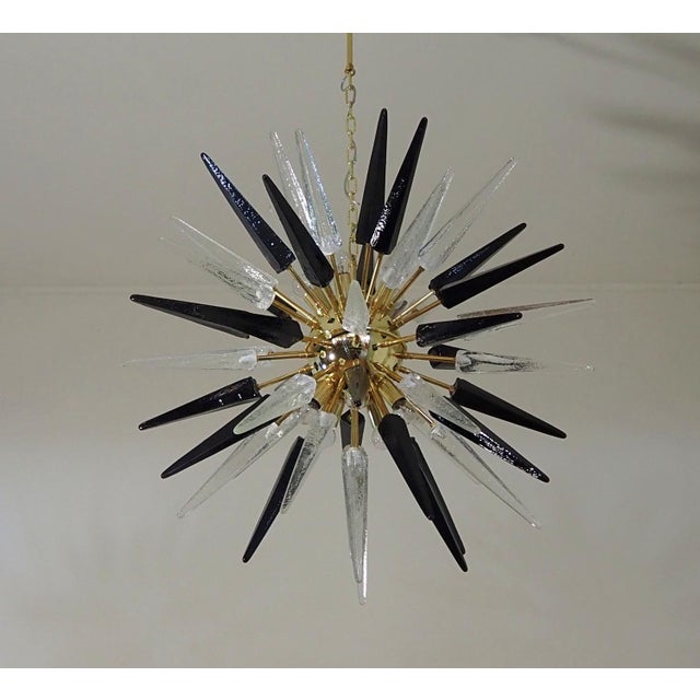 Italian Sputnik chandelier in a brass plated metal frame, 51 rare trasparent and black glass tips. Murano blown glass in a...