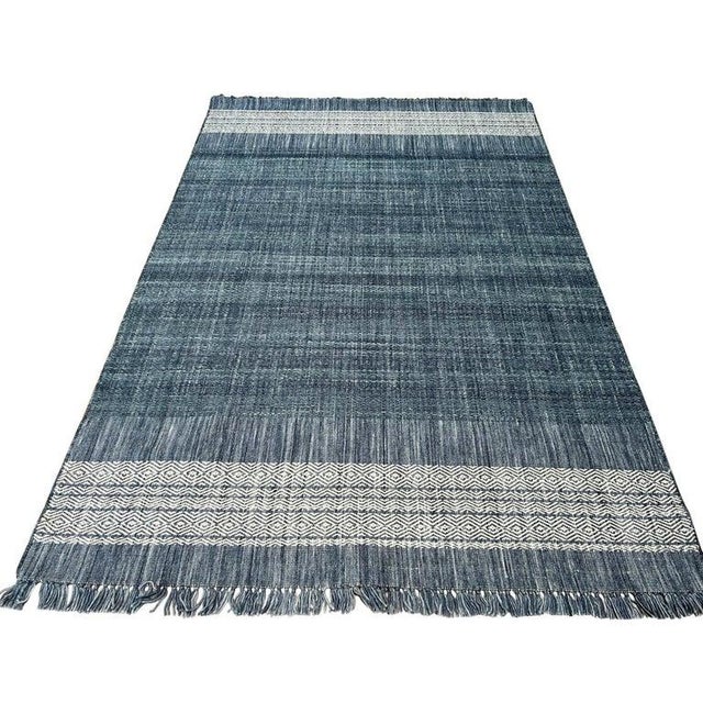 This blue wool rug features a traditional Dhurrie style construction with a flat weave technique. Handcrafted in India,...