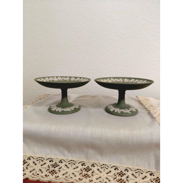 Two compotes of celadon sage green Wedgwood jasperware with a grapevine relief decoration around top and bottom. Pedestal...