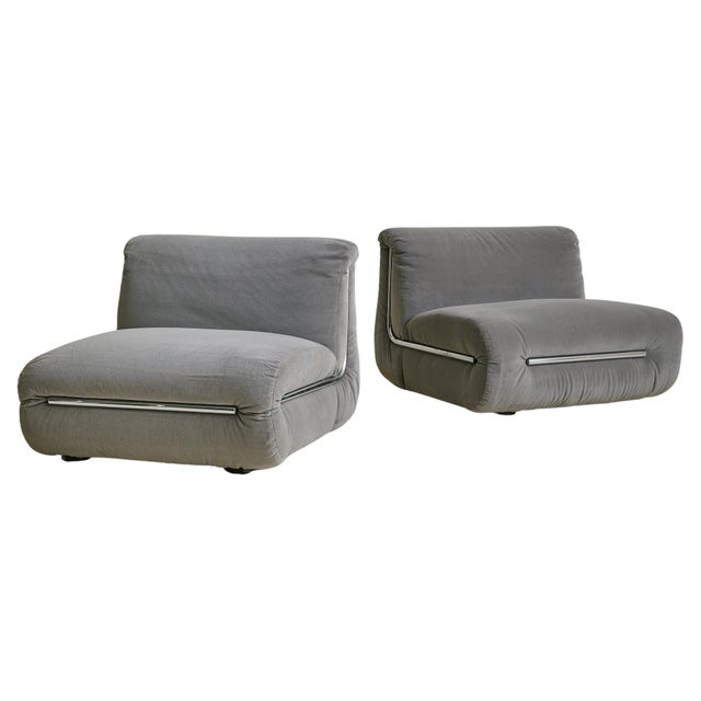 A 1970s Italian lounge chair in dove gray velvet, with a low, generous seat and gently curved back. The form is minimalist...