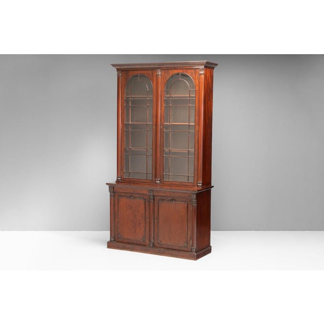 Two door bookcase with glazed arched top doors on cupboard base in mahogany (replaced cornice). U.K circa 1830.