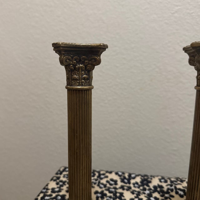 This exquisite pair of candlestick holders showcases timeless sophistication through classical architectural design....