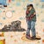 The painting shows a close embrace. In the background, you can see a destroyed house. Something has happened, something is...