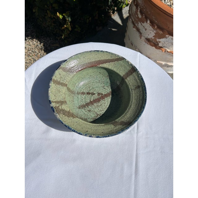 Vintage studio pottery bowl featuring a rich teal and blue glazed interior with natural tonal variation. The wide,...