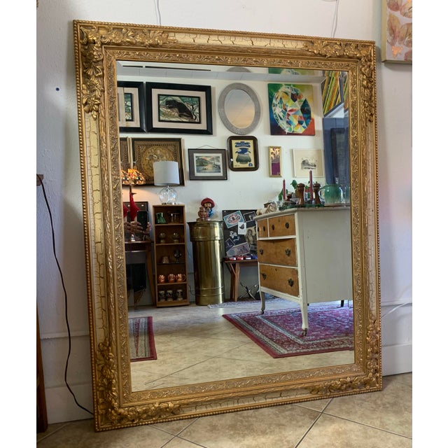 An exceptional vintage Hollywood Regency full-length wall mirror featuring an ornate gold gilt frame with elegant French-...