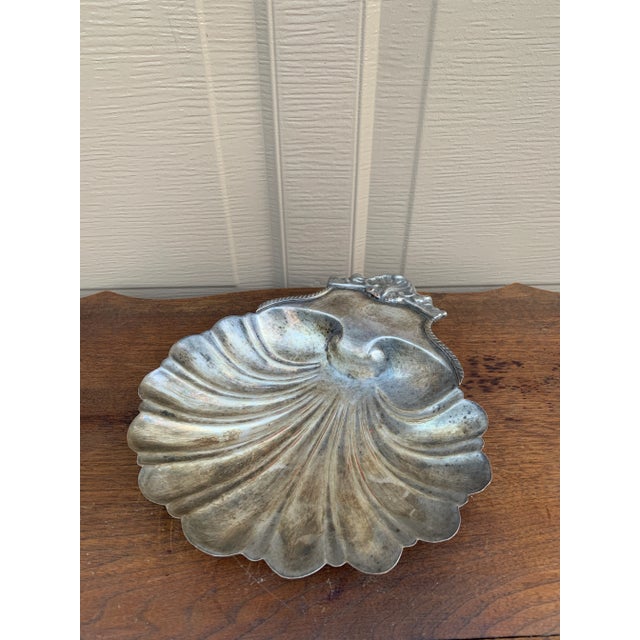 A gorgeous English Regency silver plate serving dish in the form of a scalloped clam shell, resting on three conch shell...