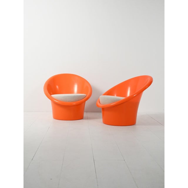 A pair of "Skopa" chairs from 1974, featuring a rigid orange plastic shell, a conical base, and cushions upholstered in...