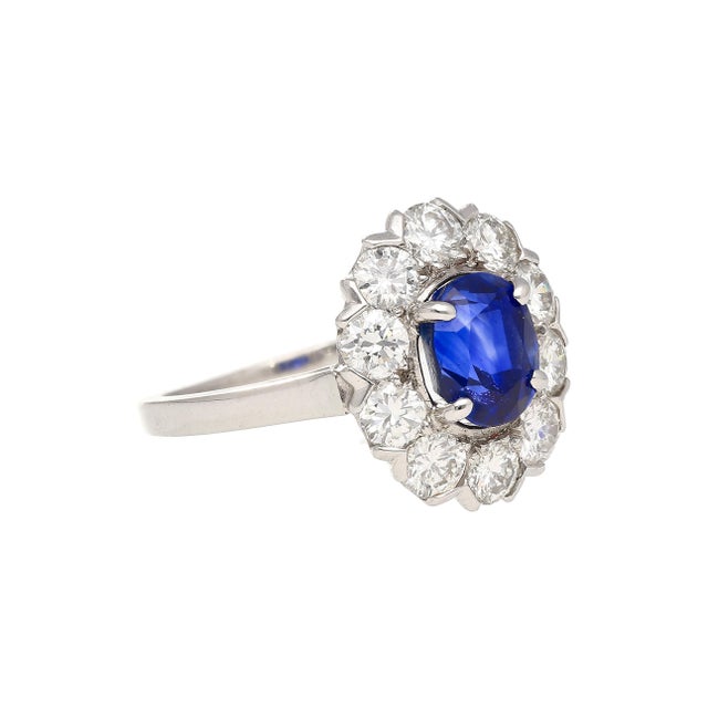 Art Deco platinum ring featuring dual-certified 1.89 carat oval blue sapphire with medium strong saturation surrounded by...