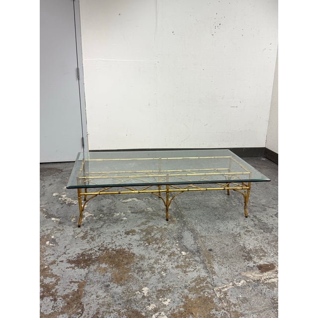 Design Plus Gallery presents a Faux Bamboo + Glass Coffee Table. The golden metal bamboo has a cross-bracing and gently...