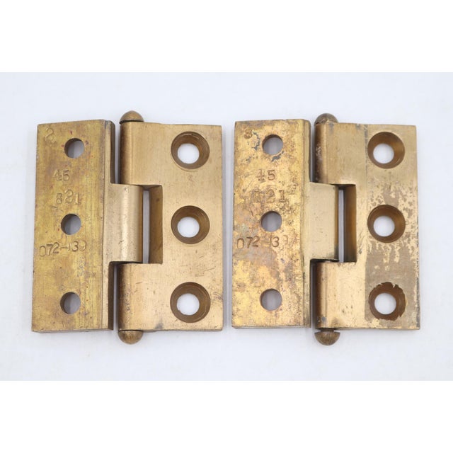 Vintage brass door hinges with button tips, three knuckles, and a template hole pattern. The original mounting screws are...