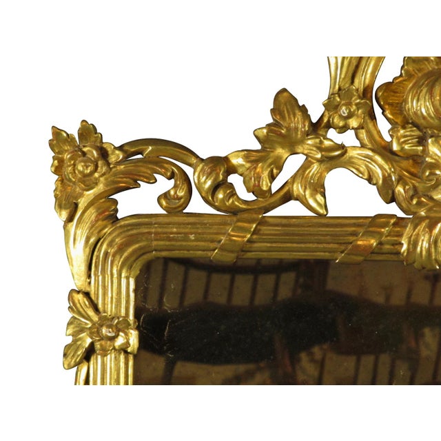 An early 20th-C. French Louis XVI giltwood mirror with extensive carved detail and water gilt surface.