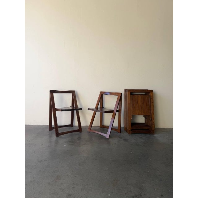 These sculptural folding chairs feature solid wood construction with clean angular frames and slatted seats. The...