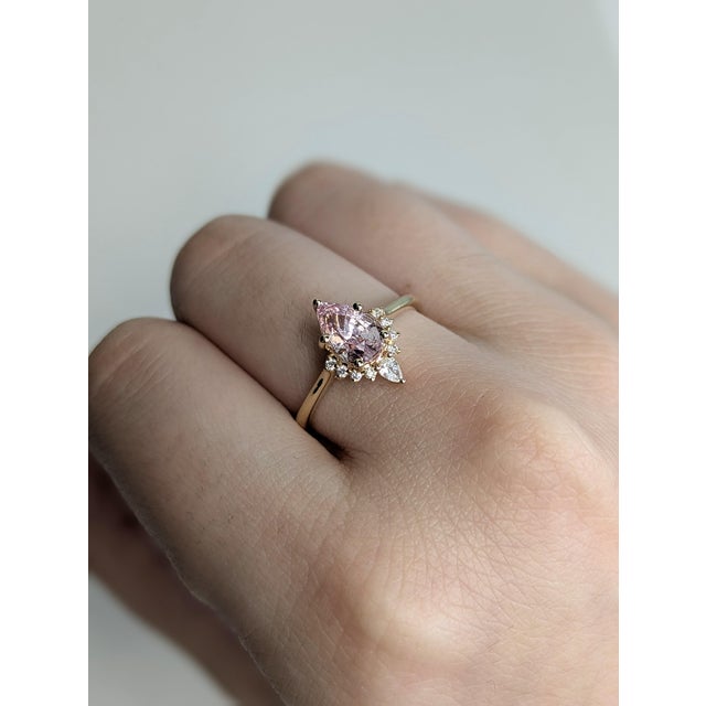 This stunning ring features a 1.11 carat intense fancy pink sapphire in a graceful pear shape, surrounded by ethically...