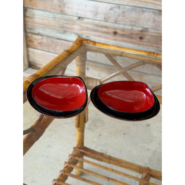 A striking pair of vintage Asian clam shell-form trinket boxes finished in richly layered lacquer with warm shades of...