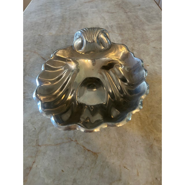 Sculptural mid-century cast aluminum bowl formed as a stylized scallop shell, featuring deeply ribbed texture, a softly...