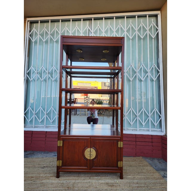 Sturdy wood display hutch has a dark reddish-brown finish. The upper section features two glass-inlay shelves and a...