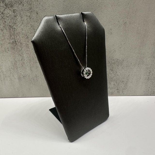 This elegant dancing diamond emerald and diamond necklace in 14kt white gold features a round emerald totaling...