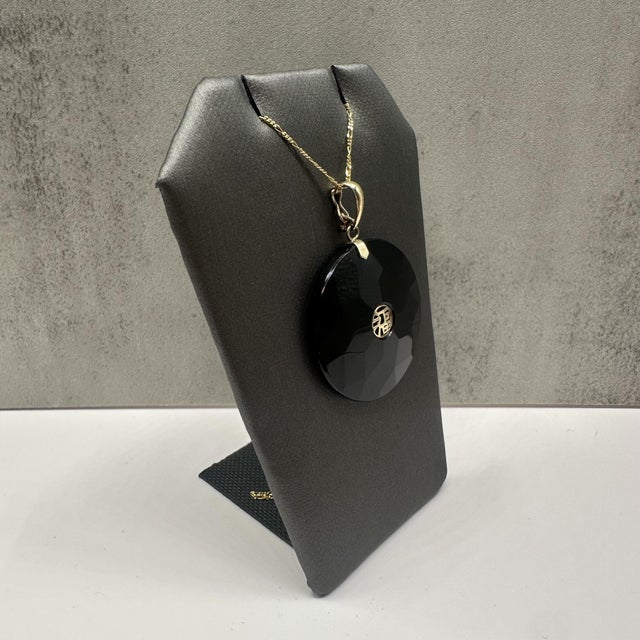 This striking black onyx necklace in 10kt yellow gold features a smooth round black onyx gemstone for a bold yet timeless...