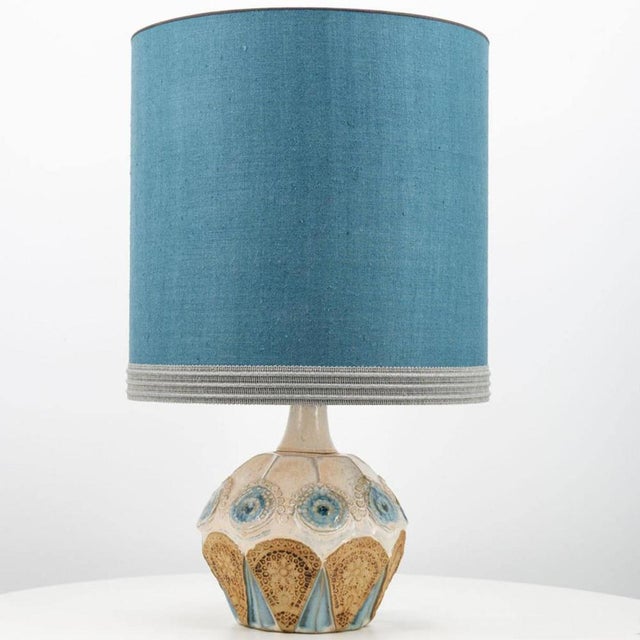 A beige ceramic table lamp with blue and brown accents. Sculptural piece, made of handmade ceramic in fresh tones, with a...