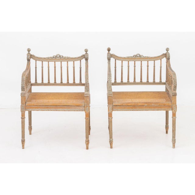 Pair of Louis XVI Style Walnut Arm Chairs, late 19th century, each with ribbon crest above spindle back and arms, cane-...