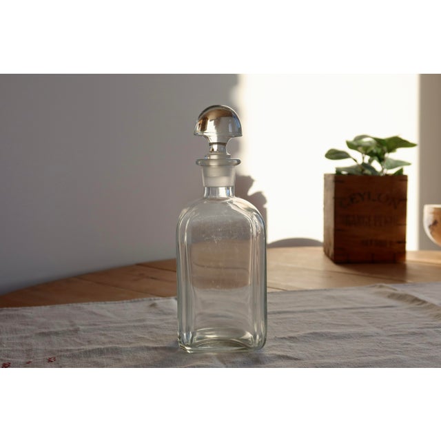 Clear glass decanter with an elegant matching mushroom stopper, featuring a simple and timeless design. Its slightly...
