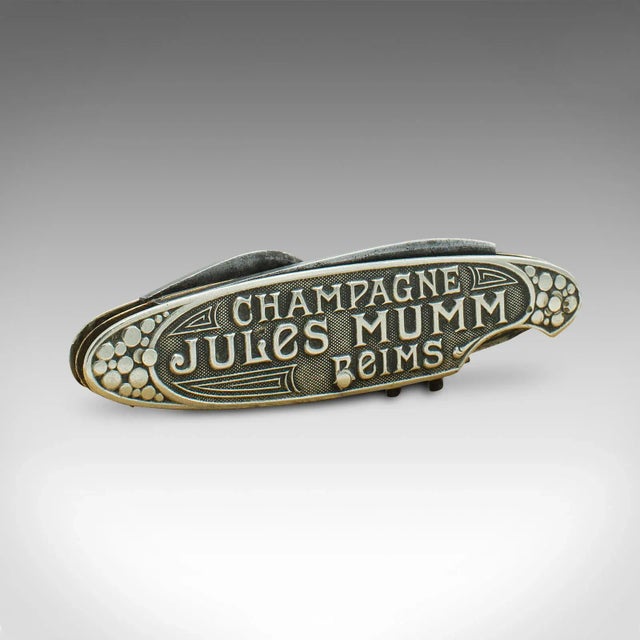 This is an antique decorative champagne corkscrew. A German, white metal and brass multi tool with Jules Mumm branding,...