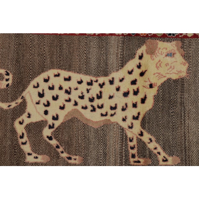Hand-knotted in wool and originating circa 1950-1959 from Afghanistan, this 2x4 vintage Gabbeh pictorial runner originates...