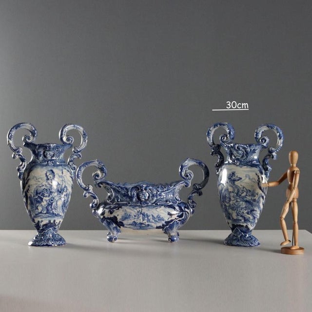Triptych of majolica ceramic fireplace vases. Decorated in shades of blue, depicting Venus and a Satyr with the cupids...