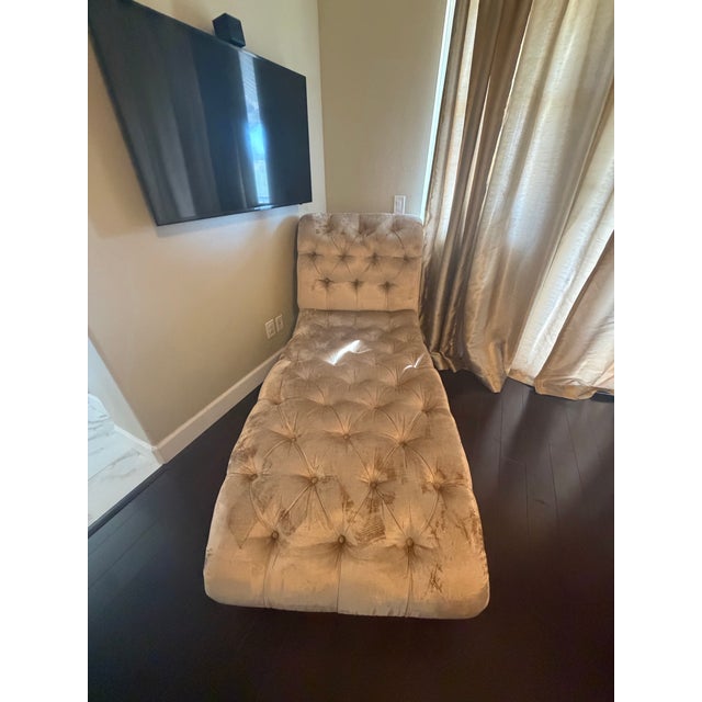 Professionally maintained chaise used as decor in guest bedroom, legs are wooden with gold detail.