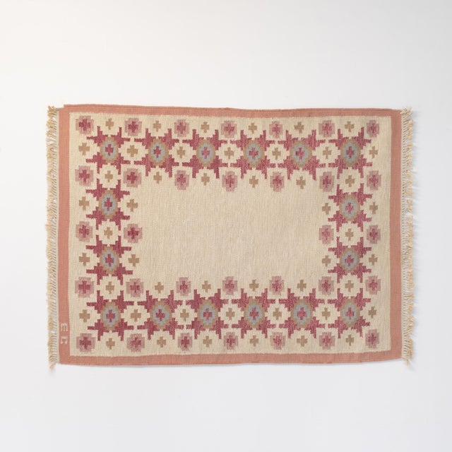Mid-Century Swedish kilim with a bold geometric pattern, in tones of reds, pinks and beige. Signed EC. Sweden circa 1960.